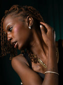Woman wearing princess cut diamond earrings with gold chains and bracelets, NYC handcrafted jewelry