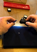 Person holding a small black device with a red tray and box in the background