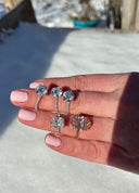 Hand holding three pairs of diamond earrings against a snowy background