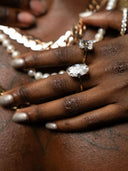 Hands wearing emerald and princess cut diamond rings with pearl necklaces, custom Queens jewelry